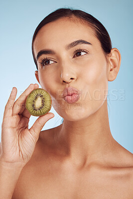 Buy stock photo Woman, thinking and kiwi for natural nutrition, diet or skincare against a blue studio background. Female person or model with organic fruit for healthy wellness, beauty or facial spa treatment