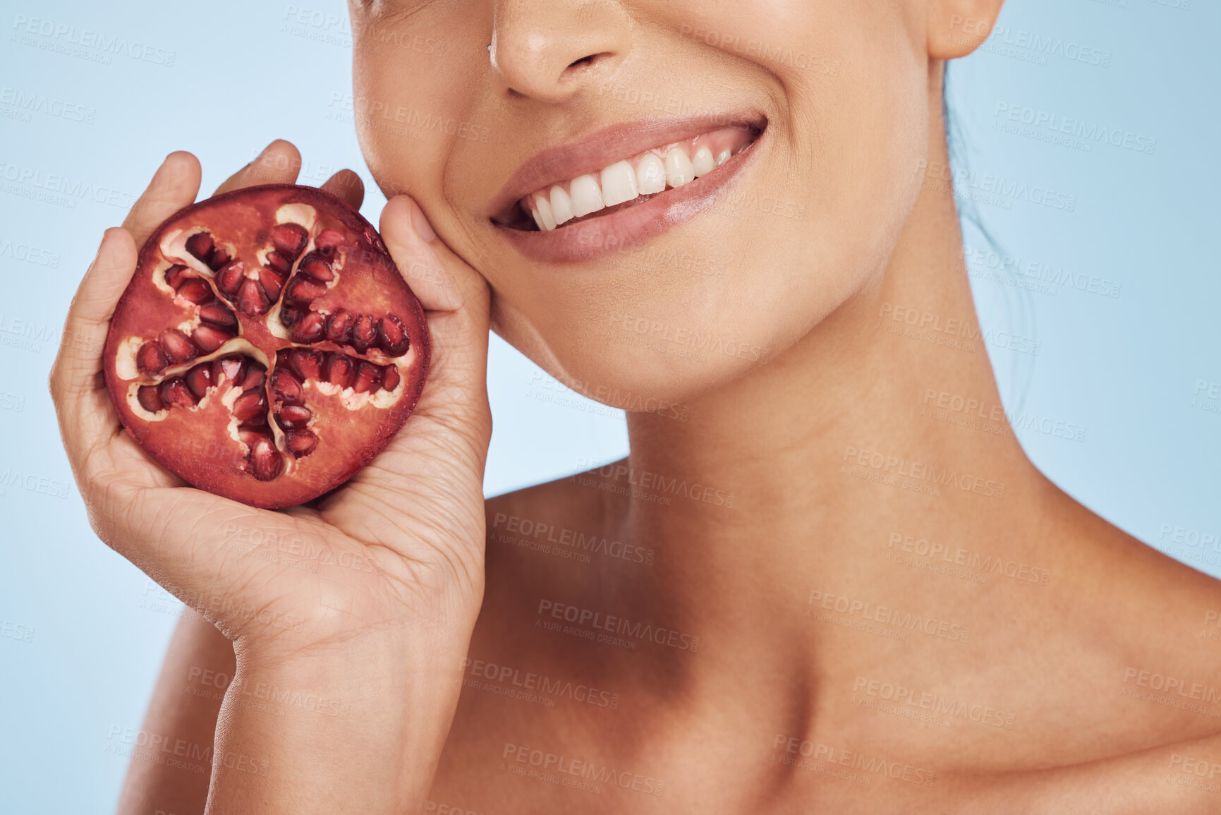 Buy stock photo Smile, skincare and hands of woman with pomegranate in studio isolated on a blue background. Natural, fruit and face of model with food for nutrition, healthy vegan diet and vitamin c for wellness.