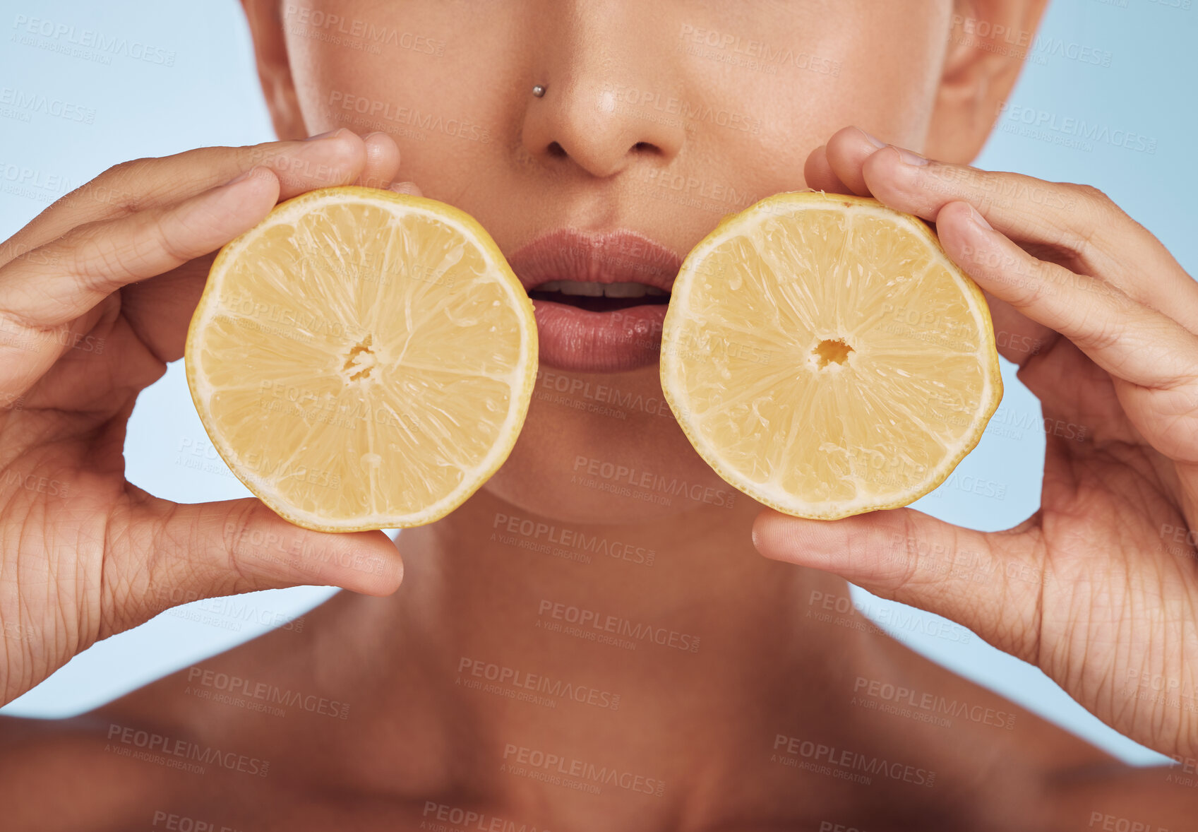 Buy stock photo Woman, hands and lemon for natural skincare, diet or detox against a blue studio background. Closeup of female person with organic citrus fruit slices for healthy wellness, collagen or vitamin C