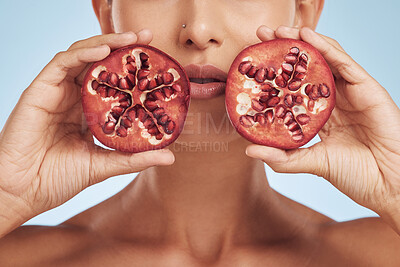 Buy stock photo Hands, skincare and woman with pomegranate for beauty in studio isolated on a blue background. Natural, fruit and face of model with food for nutrition, healthy vegan diet and vitamin c for wellness