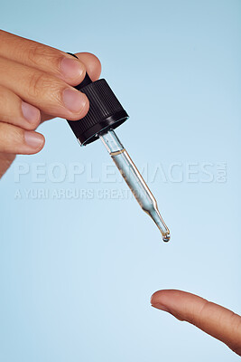 Buy stock photo Skincare oil, beauty and hands on a blue background for wellness, cosmetics and luxury. Closeup, health and a person with a serum dropper for beauty and product isolated on a studio backdrop