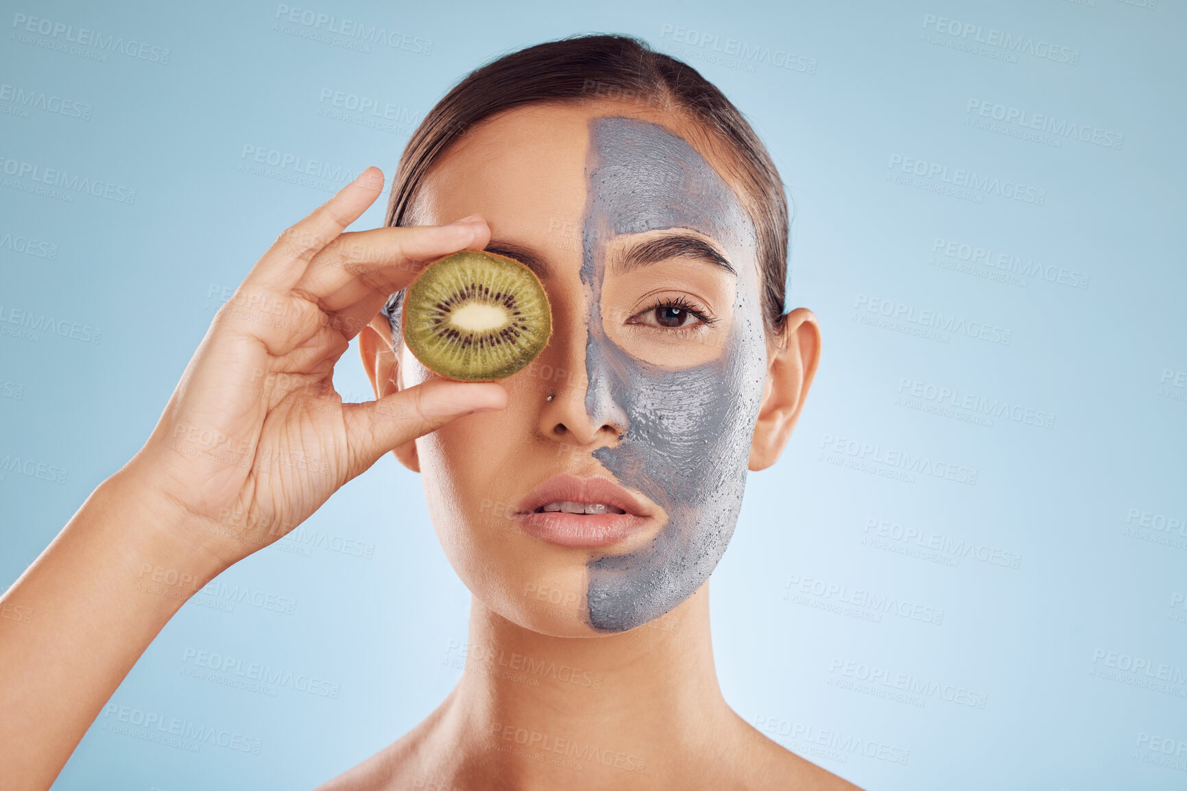 Buy stock photo Portrait, kiwi and mask for beauty with a woman in studio on a blue background for antiaging skincare. Face, facial and fruit with an attractive young female holding a berry for natural treatment