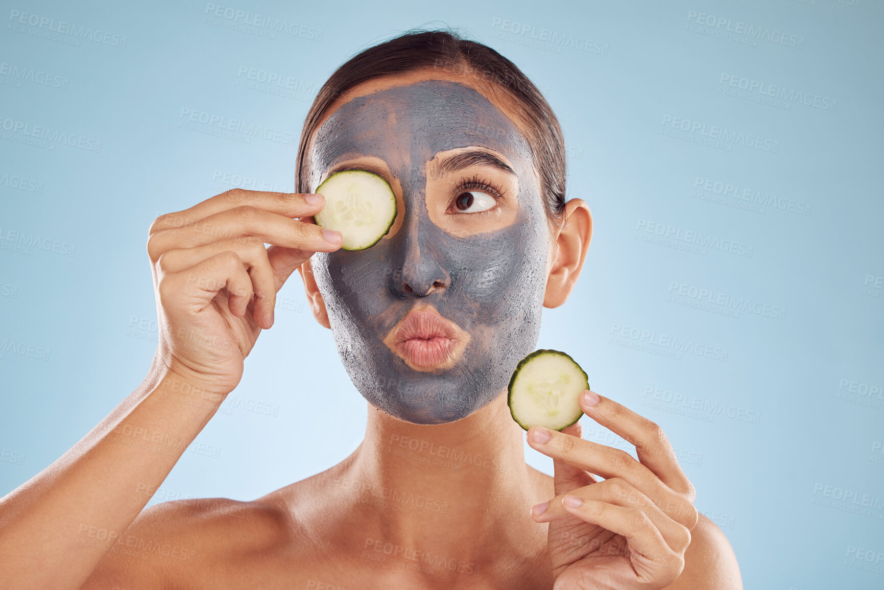 Buy stock photo Face, cucumber and mask for beauty with a woman in studio on a blue background for antiaging skincare. Facial, idea and pout with an attractive young female holding a vegetable for natural treatment