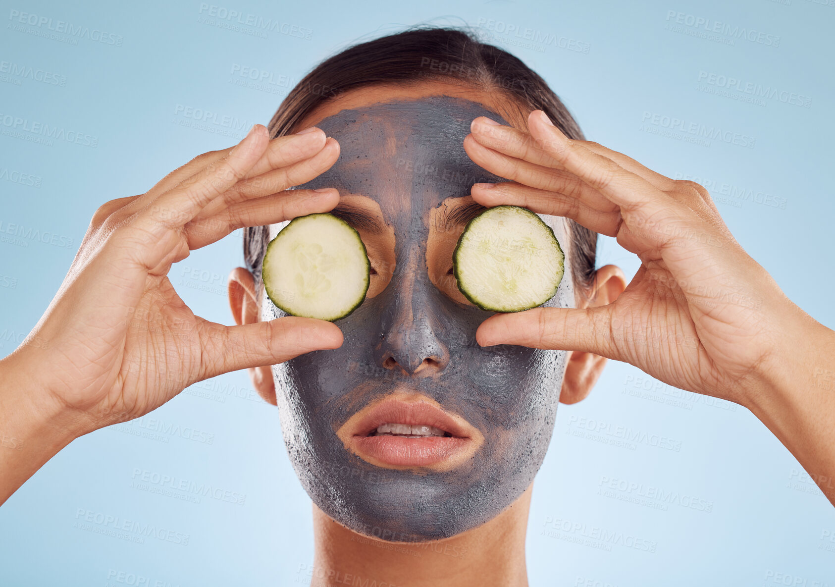 Buy stock photo Face mask, skincare and woman with cucumber on eyes for beauty in studio isolated on a blue background. Cosmetics, model and clay facial treatment with fruit, food and dermatology, health or wellness