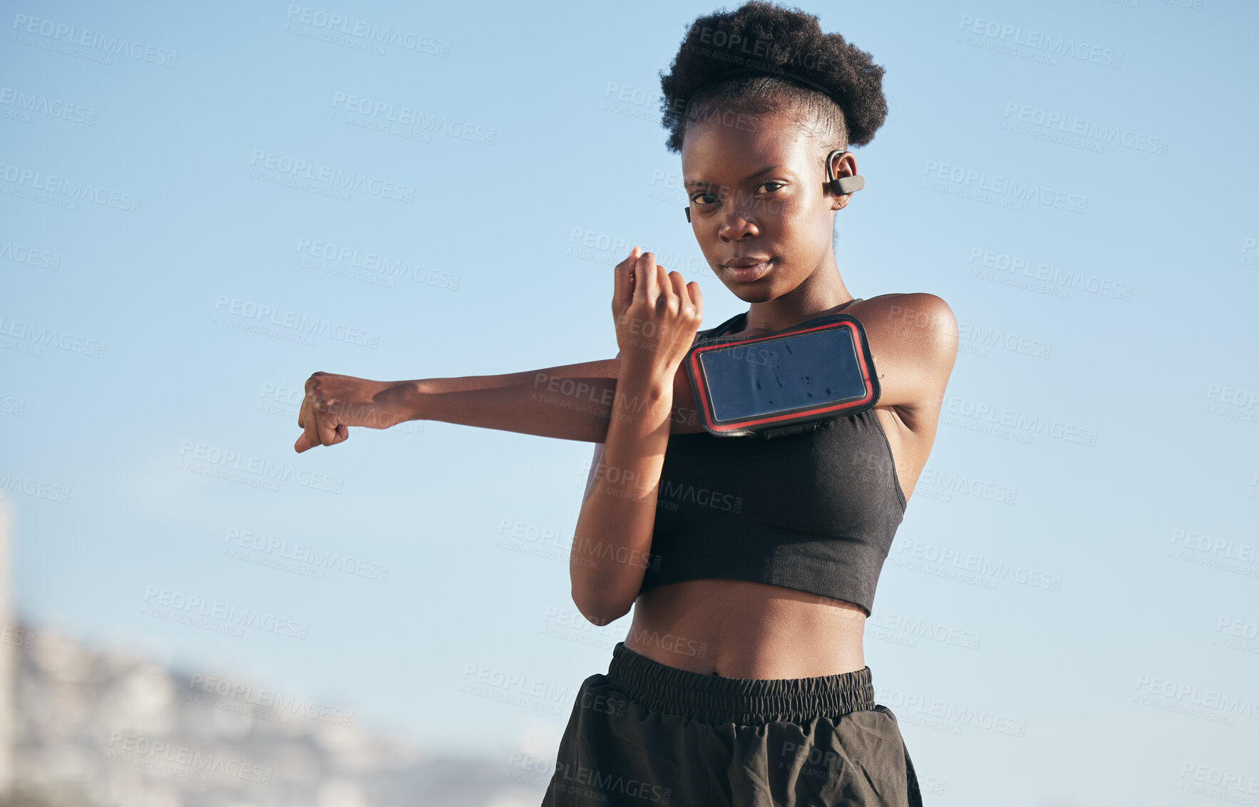 Buy stock photo Portrait, music and stretching with a black woman runner outdoor on a blurred background for cardio or endurance. Exercise, sports or warm up with a serious young athlete getting ready to workout