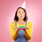 Birthday cake, studio and Asian woman blow candle, fire or flame for celebration party, present or event gift. Congratulations, wish and Japanese person with dessert, candy or food on pink background