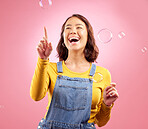 Happy, woman and laughing with bubbles in studio, pink background and excited to celebrate freedom, play and creativity. Asian female model pop soap bubble for funny, entertainment and burst of magic