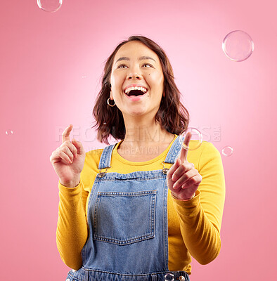 Buy stock photo Happy, woman and play with bubbles in studio, pink background and excited to celebrate freedom. Asian female model pop liquid soap bubble for fun, entertainment and burst of magic, color and creative