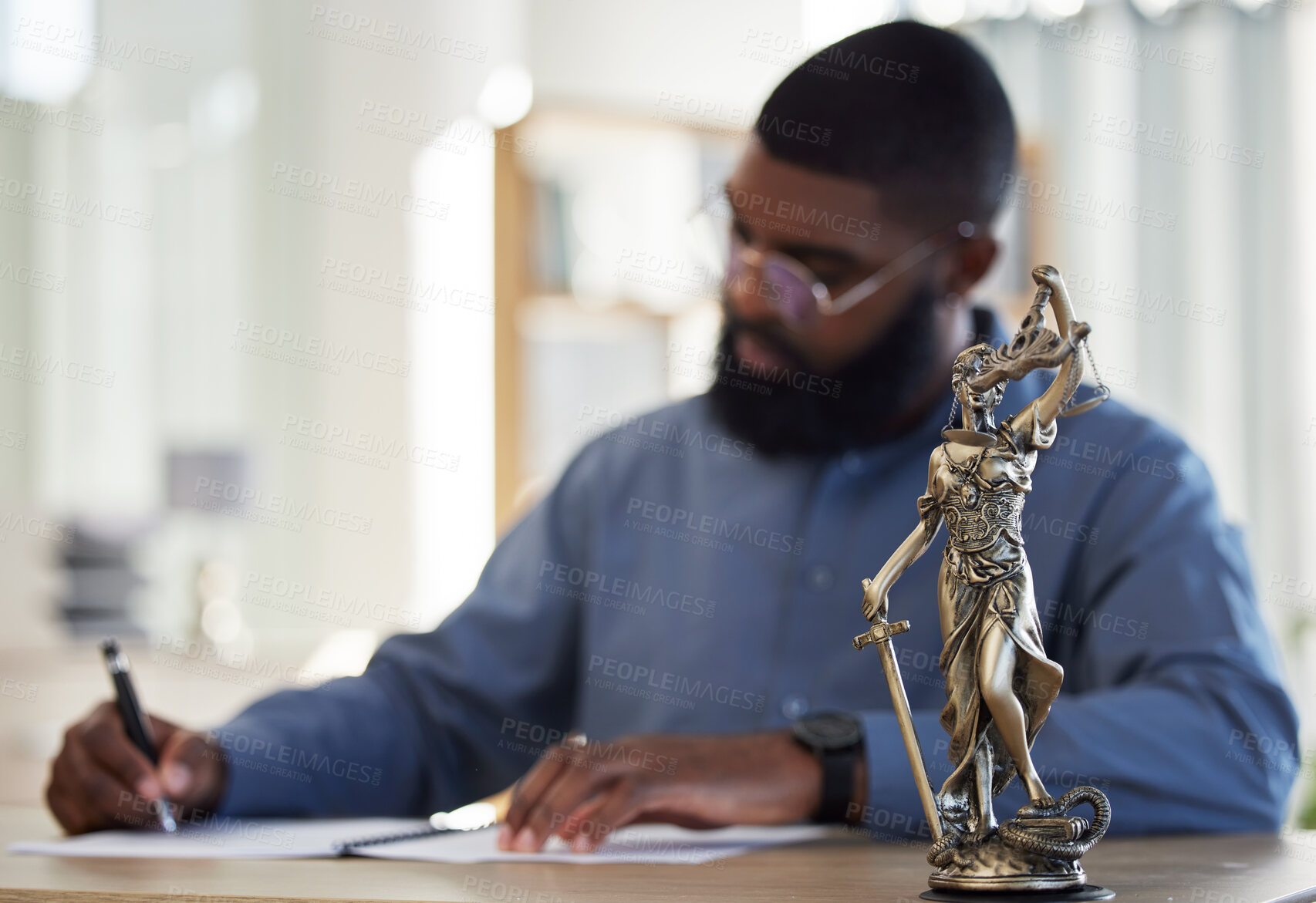 Buy stock photo Lawyer, office and man at desk with statue of justice, contract or documents for court schedule. Consultant, law firm attorney or judge with signature paperwork for legal agreement or deal in Africa.