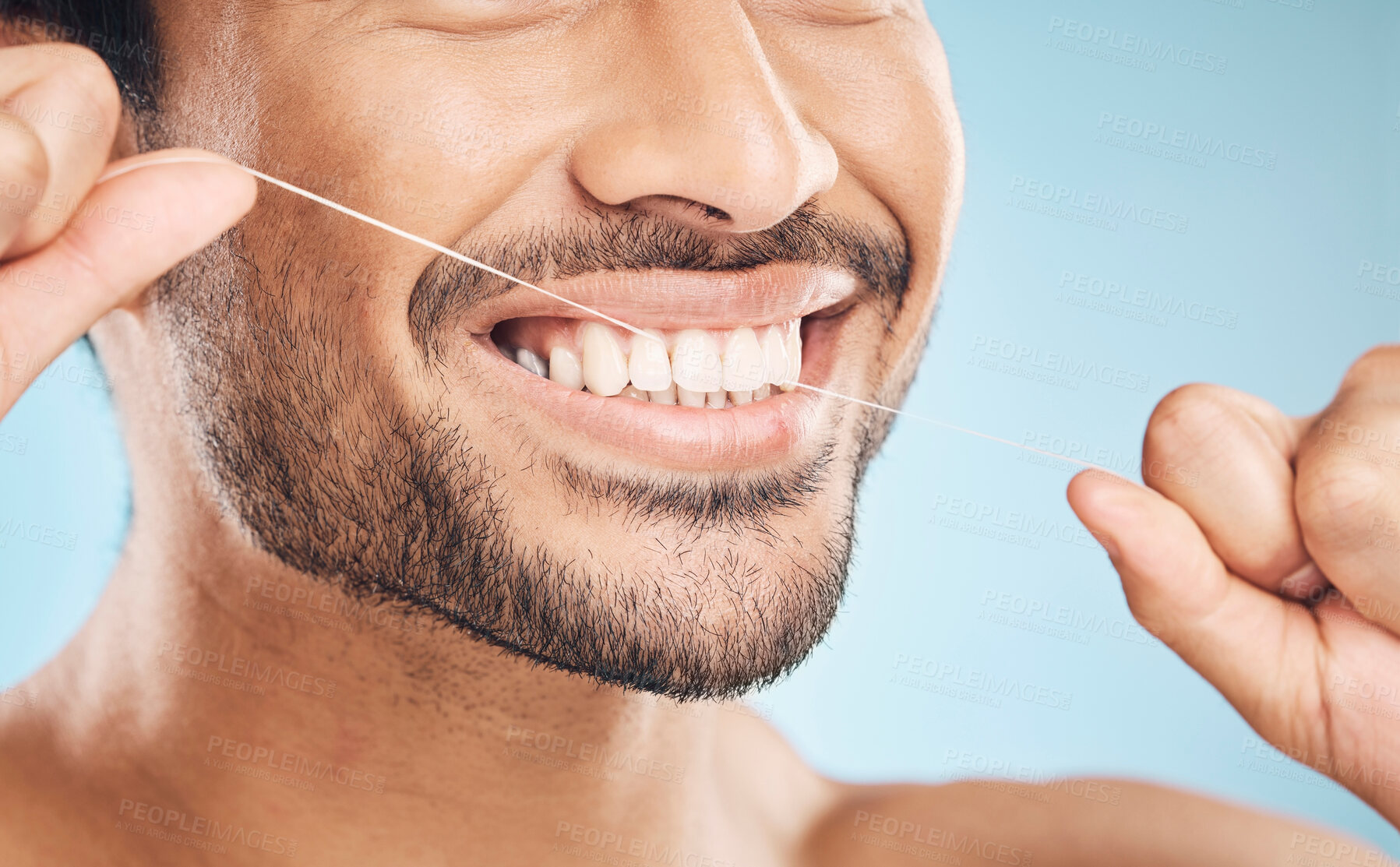 Buy stock photo Wellness, teeth closeup and flossing of a man with cleaning and dental health in a studio. Face, blue background and healthy male person with dental floss for mouth hygiene and healthcare with smile