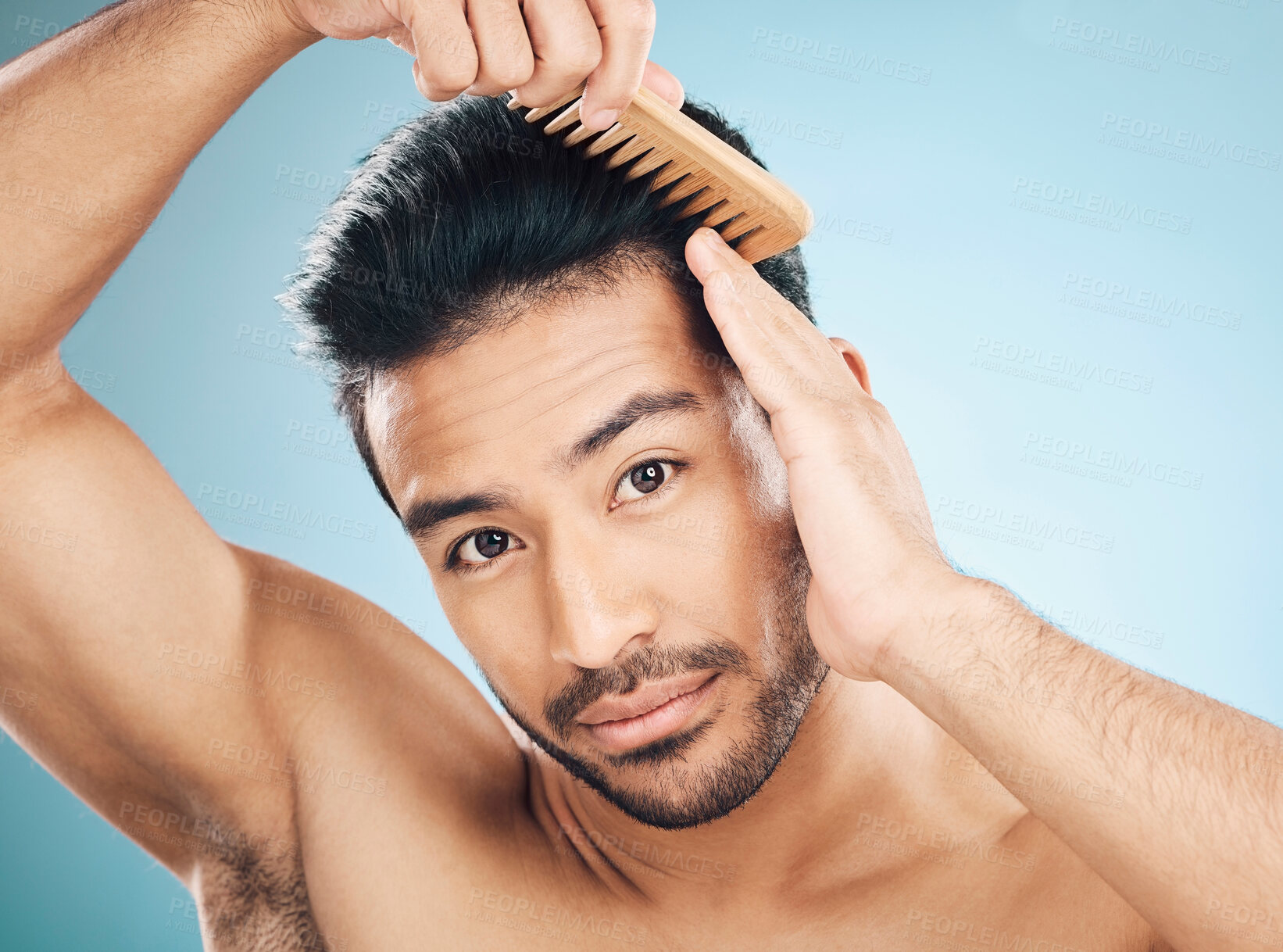 Buy stock photo Portrait, beauty and a man brushing his hair on a blue background in studio for self grooming. Face, morning and routine with a young male model in the bathroom for style after shampoo treatment