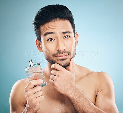 Buy stock photo Portrait, cosmetics and man with cologne, beauty or self care against a blue studio background. Face, male person or model with wellness, luxury or perfume with skincare, fragrance bottle or grooming