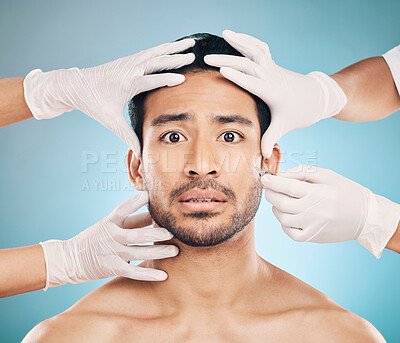 Portrait, hands and plastic surgery with a nervous man in studio on a blue background for beauty enhancement. Face, botox and change with a young male patient looking worried in a clinic for skincare