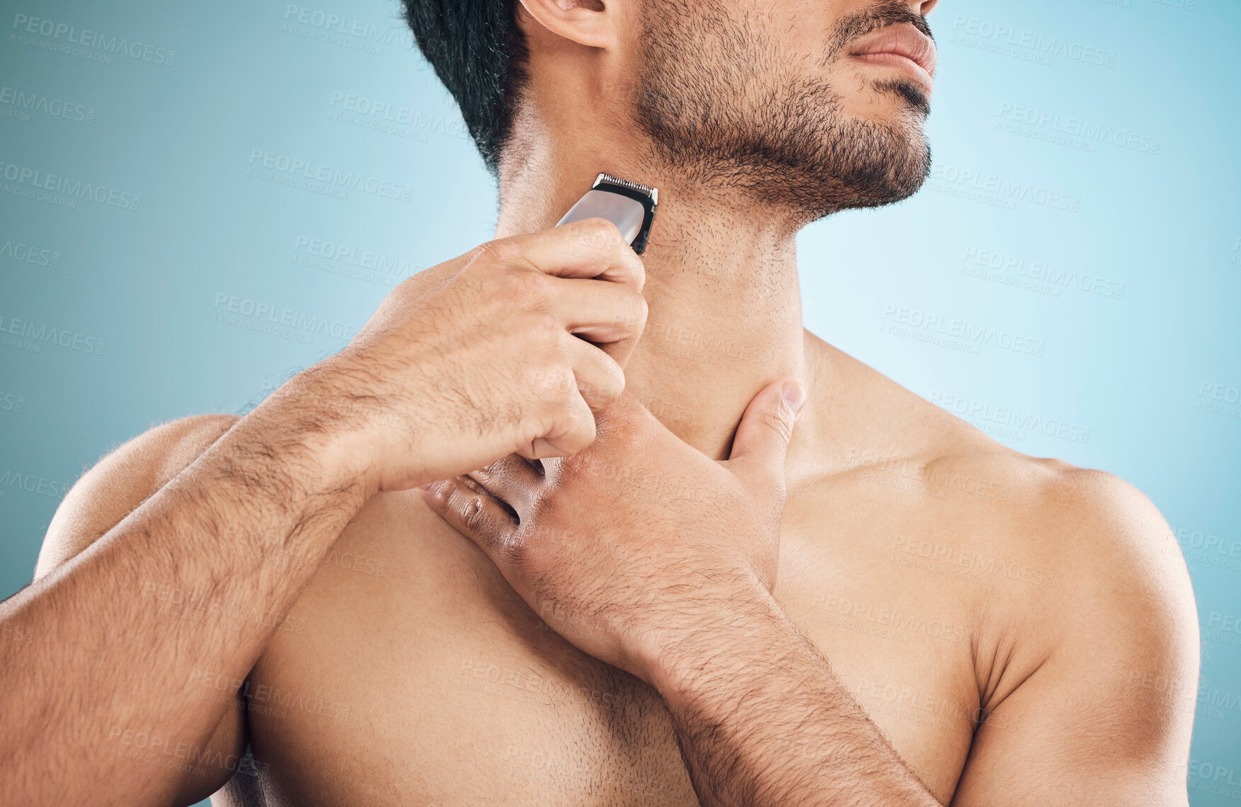 Buy stock photo Hands, shaving and electric razor with a man in studio on a blue background for personal hygiene or grooming. Beauty, wellness and cosmetics with a young male in the bathroom for hair removal