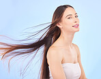 Portrait, hair and beauty with a model woman in studio on a blue background for shampoo or keratin treatment. Spa, salon or hairdresser with an attractive young female person posing for haircare