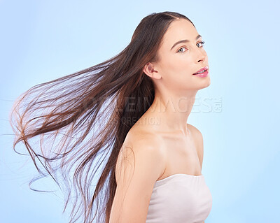Buy stock photo Portrait, hair and wind with a model woman in studio on a blue background for skincare or keratin treatment. Spa, salon and haircare with a young female person posing for beauty or shampoo promotion