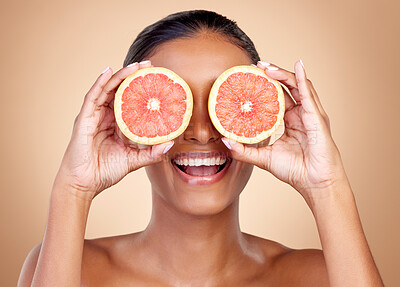 Buy stock photo Grapefruit, beauty and eyes of happy woman in studio, vitamin c nutrition or natural glow. Face of female model, healthy skincare or smile with citrus fruits, eco dermatology or sustainable cosmetics