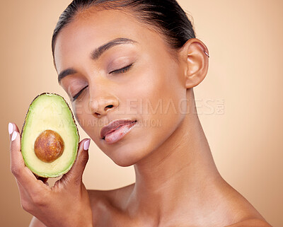 Buy stock photo Avocado, beauty and woman in studio, background and eyes closed for aesthetic glow. Face of indian model, natural skincare and fruit for sustainable cosmetics, vegan dermatology and facial benefits