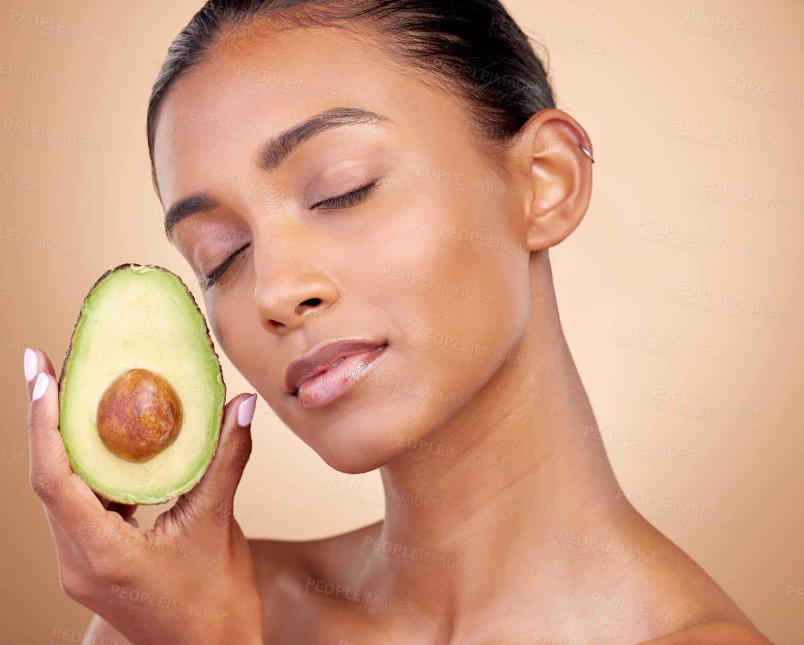 Buy stock photo Avocado, beauty and woman in studio, background and eyes closed for aesthetic glow. Face of indian model, natural skincare and fruit for sustainable cosmetics, vegan dermatology and facial benefits