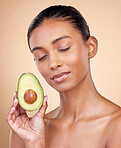 Avocado, facial beauty and woman in studio, background and omega 3 for aesthetic wellness. Face of calm indian female model, natural skincare and fruit for sustainable cosmetics, healthy food or glow