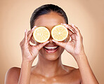Face, skincare or happy woman with lemon for health, wellness or vitality isolated on studio background. Girl, smile or female model with natural citrus fruit for vitamin c, minerals or nutrition 