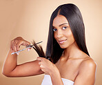 Hair, portrait and Indian woman with scissors in studio for haircut, trim or split ends repair on brown background. Haircare, face and female model with beauty tool for healthy growth, styling or tip