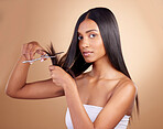 Hair, portrait and Indian woman with scissors in studio for diy, haircut or trim on brown background. Haircare, face and female model with beauty tool for healthy growth, styling or cutting tips