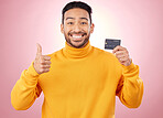 Man, thumbs up and credit card with finance, payment and loan, budget and fashion sale on studio pink background. Portrait, banking success and asian person or gen z for e commerce or shopping emoji