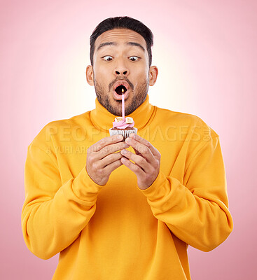 Buy stock photo Birthday, cupcake and man blowing candle in studio for celebration, party and dessert. Food, wish and flame with face of male person and cake on pink background for surprise, candy and gift mockup