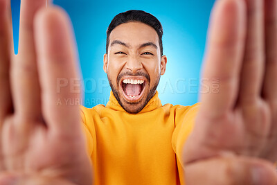 Buy stock photo Selfie, excited and portrait of a man in studio with hands and shout emoji. Face of asian male or fashion model on blue background with surprise and fun energy for social media profile picture update