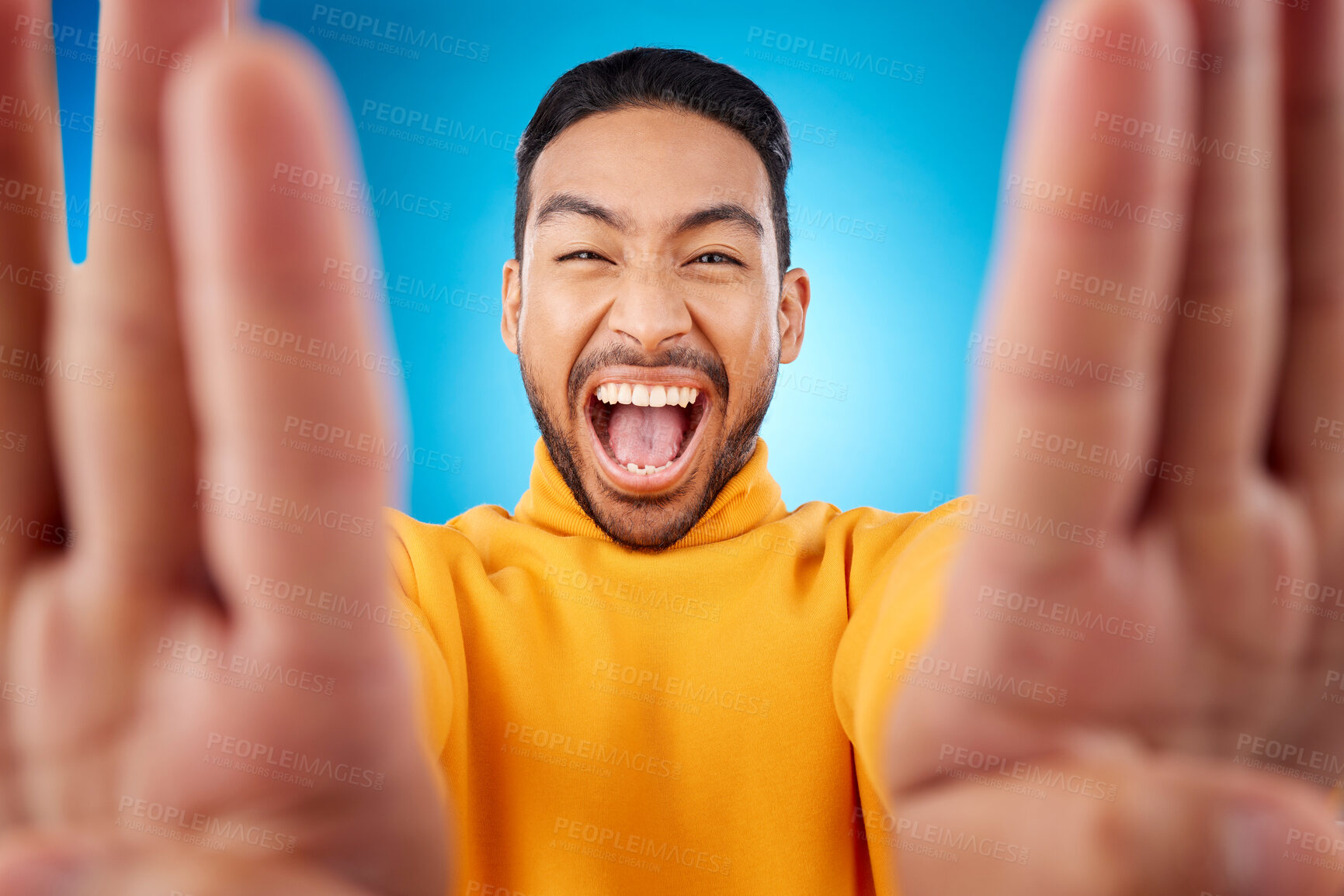 Buy stock photo Selfie, excited and portrait of a man in studio with hands and shout emoji. Face of asian male or fashion model on blue background with surprise and fun energy for social media profile picture update
