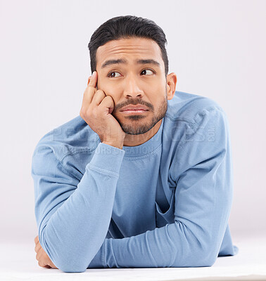 Buy stock photo Thinking, remember and young man in a studio resting on his arms with a contemplating facial expression. Happy, smile and Indian male model with question or dreaming face isolated by white background