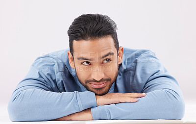 Buy stock photo Thinking, dreaming and young man in a studio resting on his arms with a contemplating facial expression. Happy, smile and Indian male model with question or remember face isolated by white background