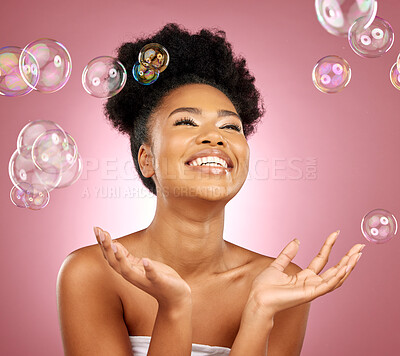 Buy stock photo Beauty, bubbles and a happy woman with skin care in studio for wellness and dermatology glow. Happy, natural makeup and face cosmetics of a black female model with facial shine on a pink background