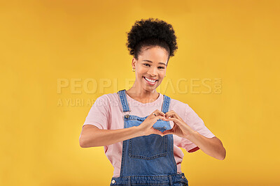 Buy stock photo Hands, black woman and sign for a heart, love and portrait of care or support on yellow background in studio. Happy, face and girl with hand gesture for loving, kindness or emoji for caring mindset