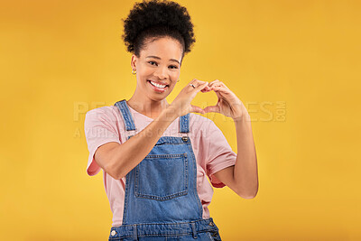 Buy stock photo Black woman, hands and sign for a heart, love and portrait of care or support on yellow background in studio. Happy, face and girl with hand gesture for loving, kindness or emoji for caring mindset
