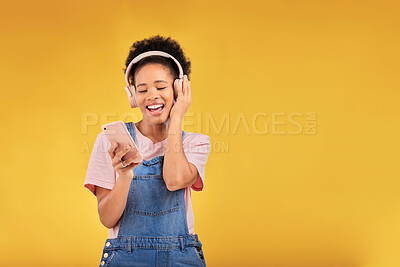 Buy stock photo Music, headphones and happy black woman with phone in studio isolated on a yellow background mockup space. Person, excited and listen to radio, podcast or sound for jazz, hip hop or streaming audio