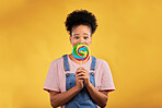 Portrait, black woman with candy or lollipop in studio on yellow background and eating sweets, dessert or food with sugar. Gen z, face of girl and hungry for delicious treats, snack or product
