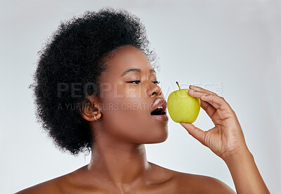 Buy stock photo Black woman, hair and apple for natural nutrition, diet or vitamins against a white background in studio. Face of African female person eating organic fruit for healthy wellness, fiber or body care