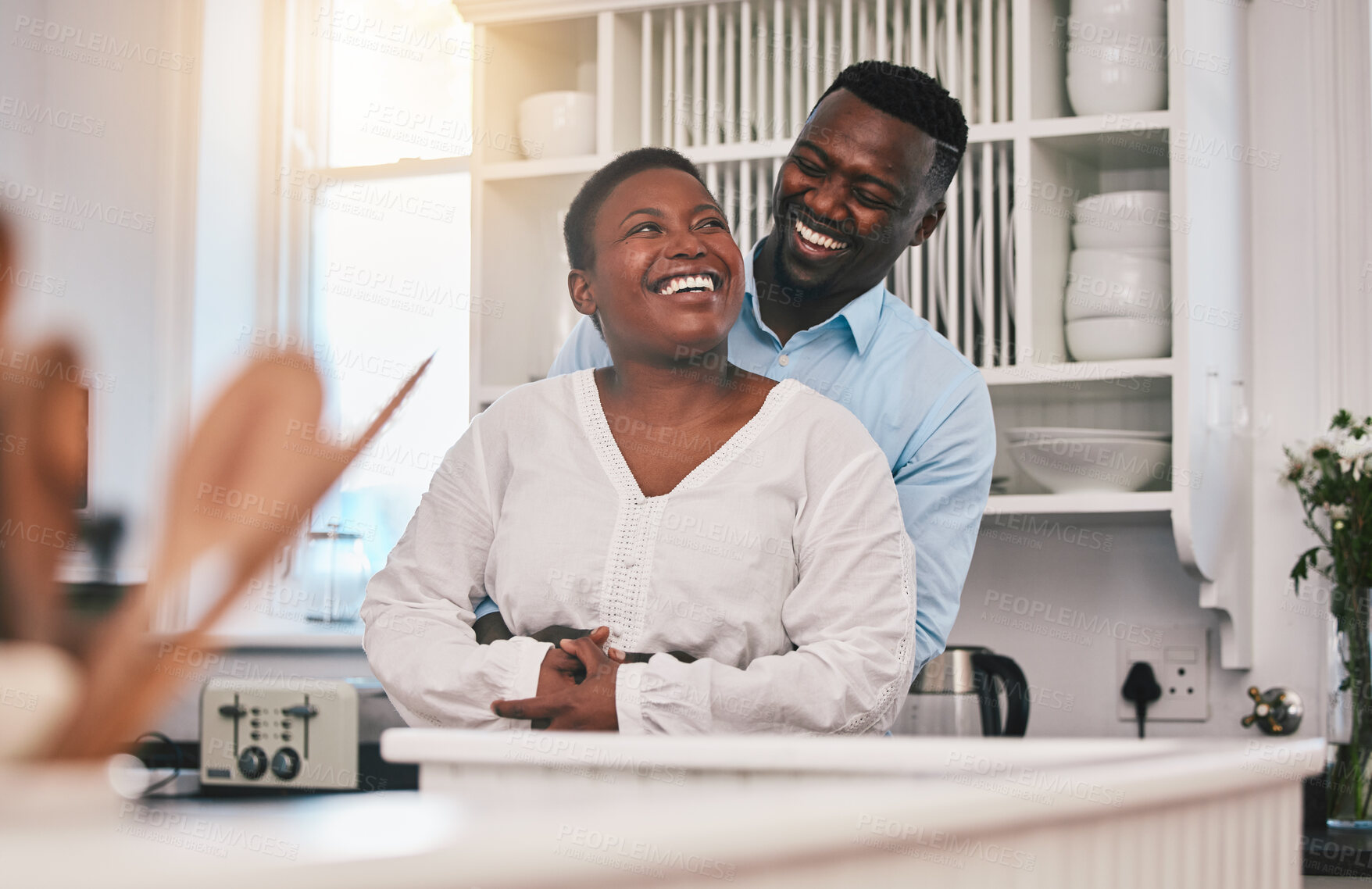 Buy stock photo Hug, kitchen and happy black couple laugh, bond or enjoy quality time together, funny conversation or chat in Nigeria home. Love, marriage and African people humour, embrace and smile at comedy joke