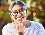 Portrait, smile and blowing a kiss with a woman on a nature green background for love or romance. Face, glasses and flirt with a happy young female person standing in a garden on valentines day