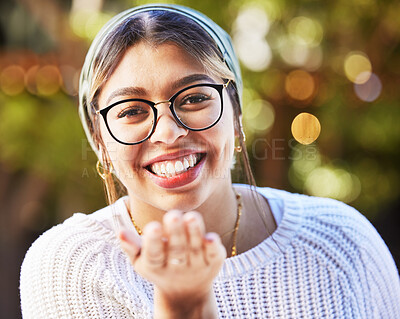 Buy stock photo Portrait, smile and blowing a kiss with a woman on a nature green background for love or romance. Face, glasses and flirt with a happy young female person standing in a garden on valentines day