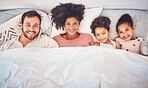Family, happy and portrait in bed at home for quality time, bonding or morning routine. Above, mixed race and smile of a man, woman and children together in a bedroom with love, care and comfort