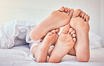 Feet, love and a couple in bed to relax in the morning while bonding in their home for trust or support. Bedroom, sleeping or dreaming with a man and woman resting closeup under a blanket in a house