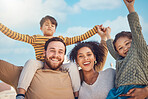 Portrait, motivation and piggyback with a family cheering together against a blue sky background. Diversity, love or smile with parents and children in the garden of their home for trust or support
