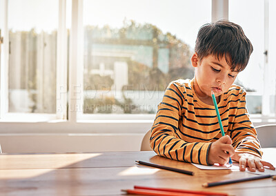 Buy stock photo Drawing, education and a child in a house at a table for art, learning writing or creativity. Serious, morning and a kid with paper and color at a desk in a home for knowledge, studying or a picture