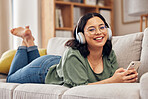 Woman, portrait and headphones with smartphone on sofa, for hearing radio, online subscription and podcast. Happy female person listening to music, streaming audio and sound on mobile in living room