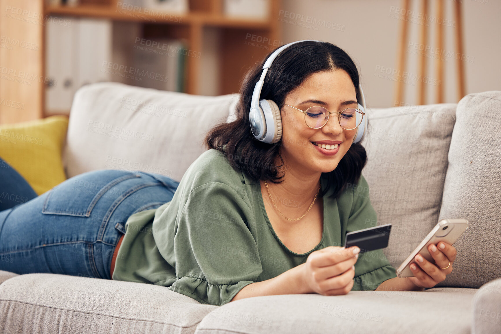 Buy stock photo Woman, credit card and phone on sofa, home and headphones with smile, online shopping or payment on web. Girl, smartphone and fintech app for cybersecurity, discount and deal with e commerce store