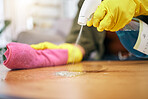 Person, hands and spray on table with cloth for hygiene, bacteria or germ removal at home. Closeup of cleaner, housekeeper or maid wiping furniture in domestic service or disinfection on desk surface