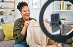 Fashion, live streaming and a black woman content creator unboxing a clothes outfit in her home. Social media, brand deal and a happy female influencer recording a broadcast for subscription service